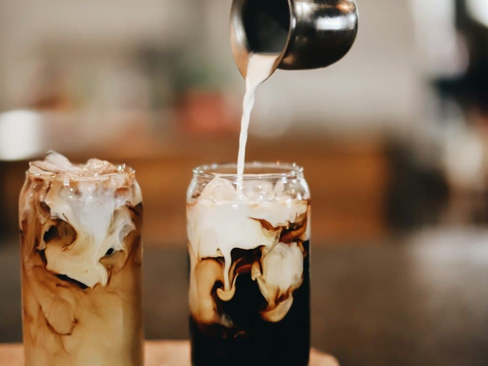 Milk being poured into iced coffee